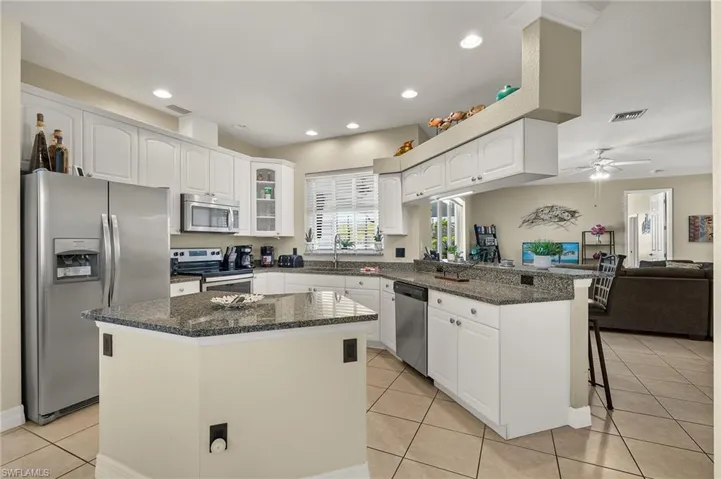 Kitchen featuring a center island, ceiling fan, appliances with stainless steel finishes, kitchen peninsula, and a breakfast bar area