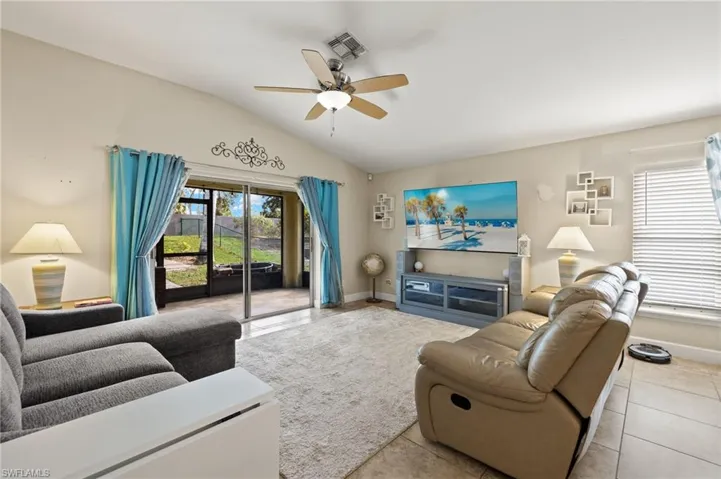 Tiled living room with a wealth of natural light, ceiling fan, and lofted ceiling