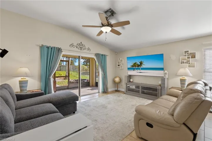 Tiled living room with ceiling fan and vaulted ceiling