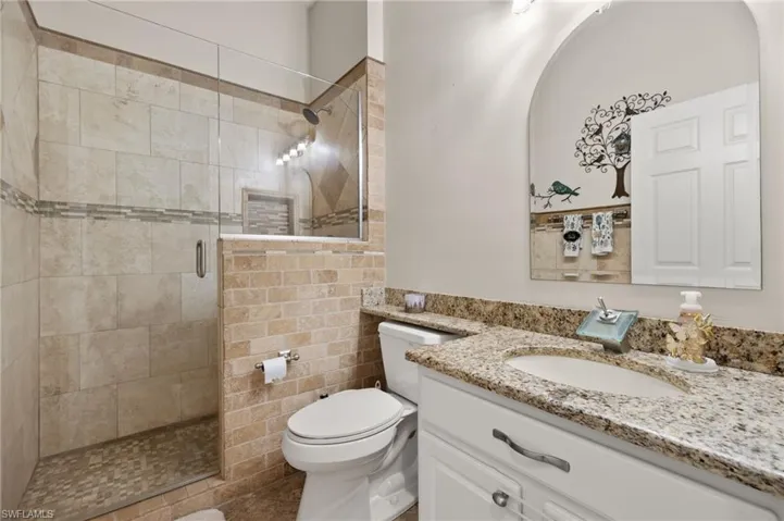 Bathroom featuring vanity, an enclosed shower, and toilet