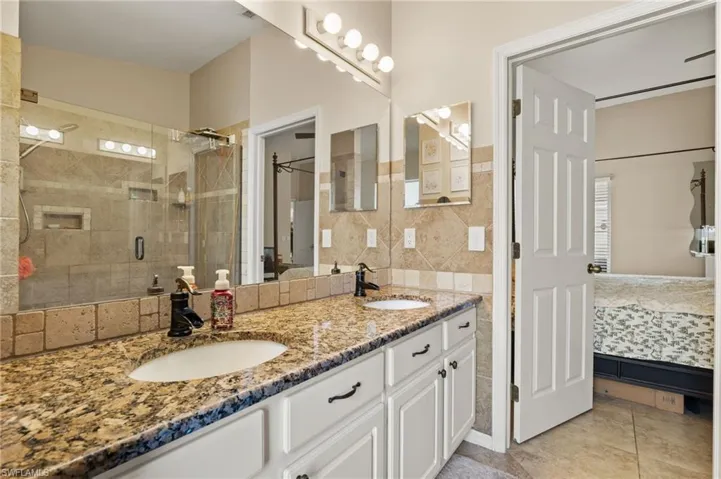 Bathroom featuring vanity, tile walls, tile patterned floors, and a shower with door