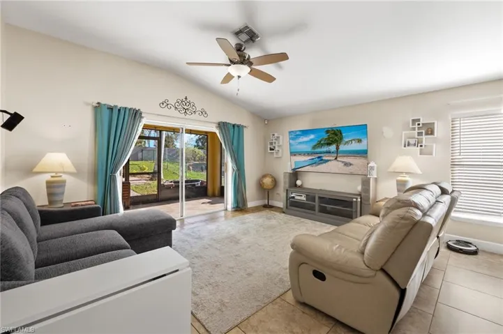 Living room featuring ceiling fan, light tile patterned floors, and lofted ceiling