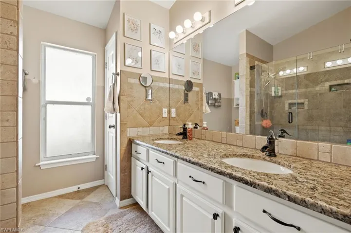 Bathroom with decorative backsplash, lofted ceiling, vanity, walk in shower, and tile patterned flooring