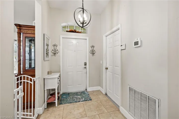 Tiled entryway featuring a towering ceiling and a notable chandelier