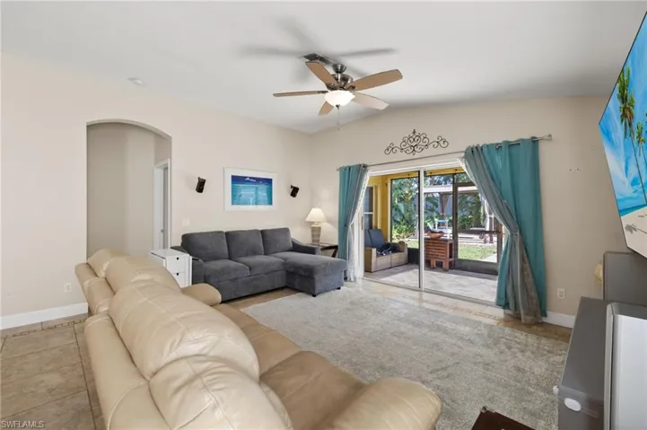 Living room with light tile patterned floors, ceiling fan, and lofted ceiling