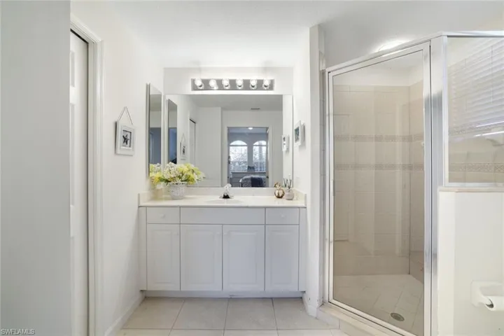 Full bathroom featuring a shower stall, connected bathroom, and light tile patterned flooring