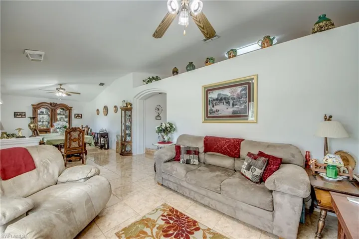 Living area with ceiling fan, arched walkways, and tile patterned floors