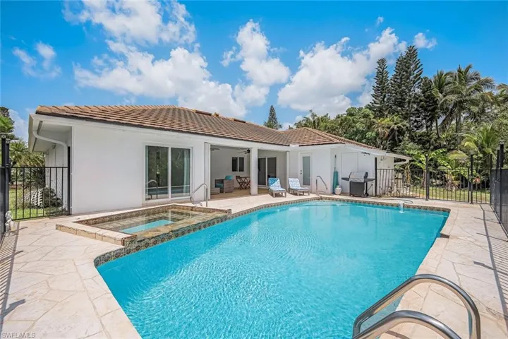 View of swimming pool featuring a patio area, grilling area, and a pool with connected hot tub