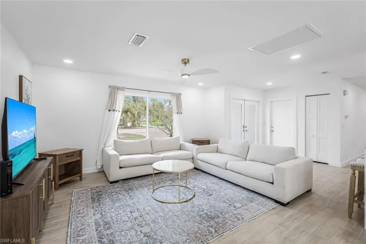 Living room with a ceiling fan, light wood-style floors, recessed lighting, and attic access