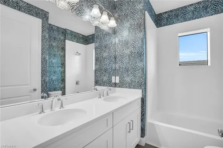 shared Full bathroom featuring vanity with extensive cabinet space, dual sinks, toilet, and  shower combination