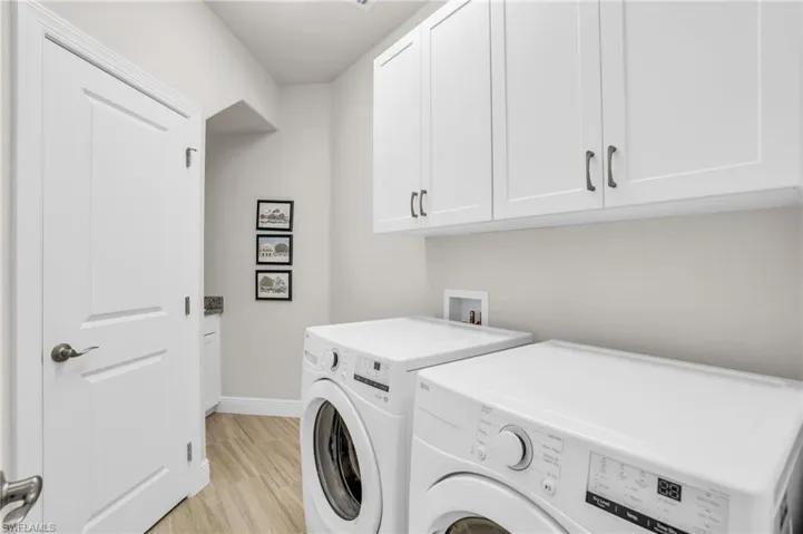 Laundry area featuring cabinets, washing machine and dryer, washer hookup, and light hardwood / wood-style flooring also has a sink