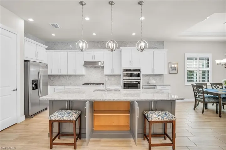 Kitchen featuring stainless steel appliances, tasteful backsplash, light hardwood / wood-style floors, and pendant lighting