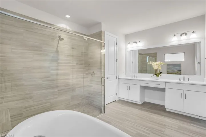 Bathroom featuring dual bowl vanity, shower with separate bathtub, and hardwood / wood-style floors