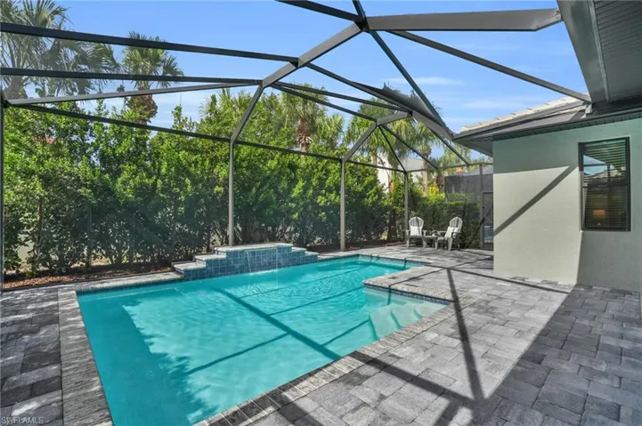 View of swimming pool with a patio, glass enclosure, and pool water feature