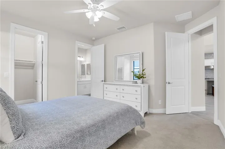 Carpeted bedroom with ceiling fan and ensuite bath
