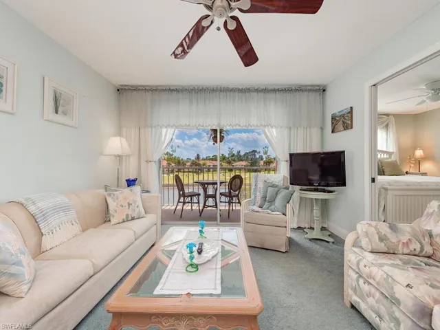 Carpeted living room featuring baseboards and a ceiling fan