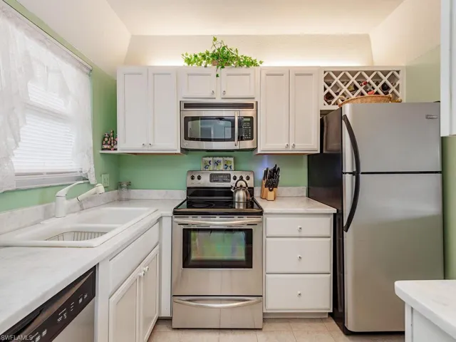 Kitchen featuring white cabinets, light countertops, a sink, and stainless steel appliances