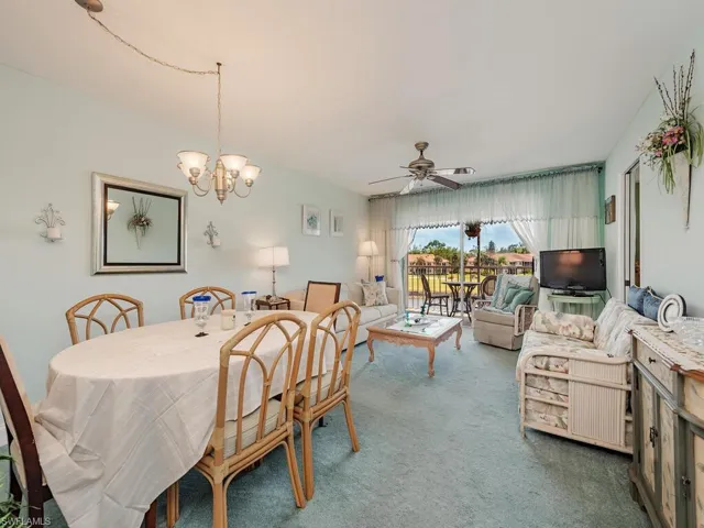 Dining space featuring carpet and ceiling fan with notable chandelier