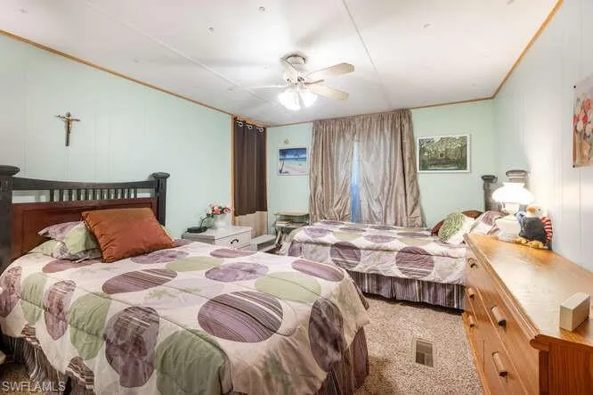 Bedroom with carpet flooring, ceiling fan, and crown molding