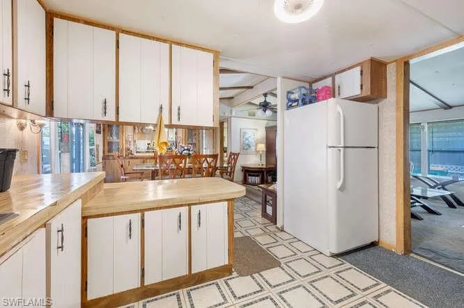 Kitchen featuring ceiling fan, white fridge, plenty of natural light, and white cabinetry