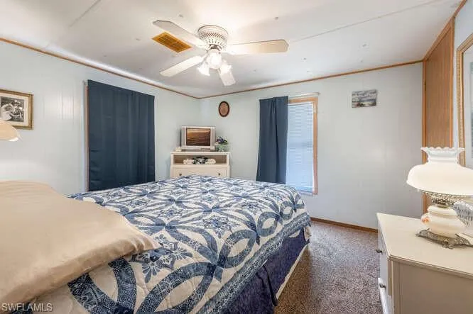 Carpeted bedroom with ceiling fan and crown molding