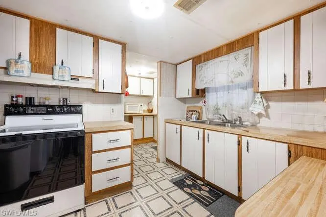 Kitchen with white cabinets, white appliances, and sink