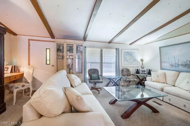 Living room with vaulted ceiling with beams and carpet floors