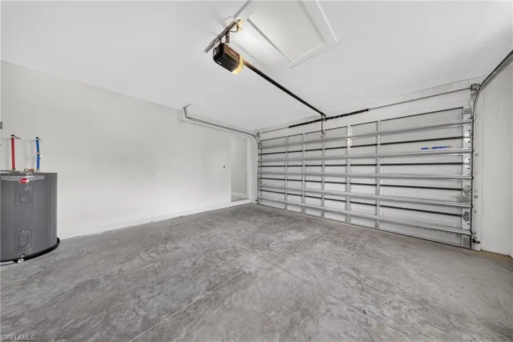 Spacious garage featuring concrete flooring, a large overhead door, and a built-in water heater