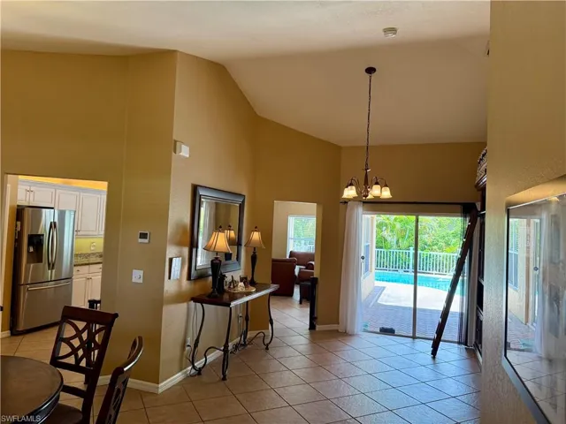 Dining space featuring high vaulted ceiling, light tile patterned flooring, and a chandelier