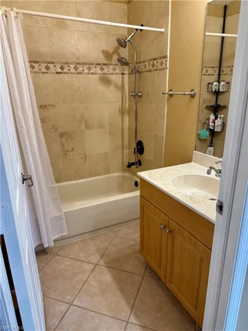 Full bath featuring shower / bathtub combination with curtain, vanity, and tile patterned flooring