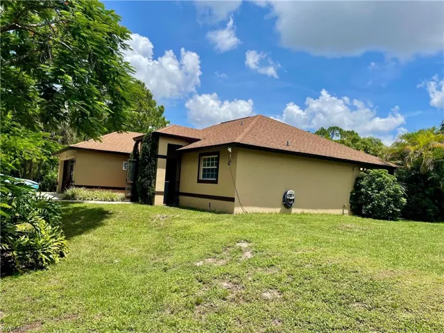 Back of house featuring stucco siding and a yard