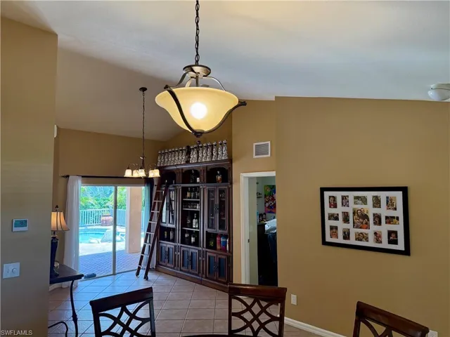 Tiled dining area featuring a chandelier and high vaulted ceiling