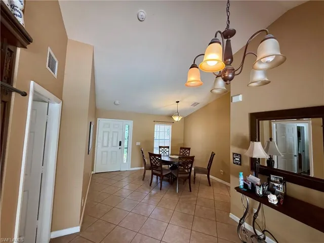 Dining space with light tile patterned flooring, high vaulted ceiling, and a chandelier