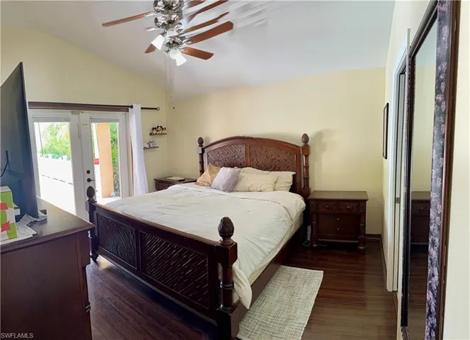Bedroom featuring lofted ceiling, dark wood finished floors, access to exterior, and a ceiling fan