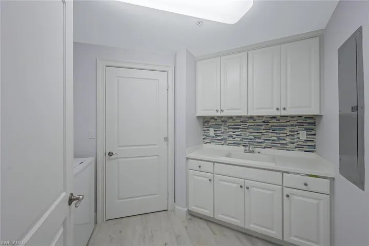 Laundry area featuring sink, light hardwood / wood-style flooring, and washer / clothes dryer