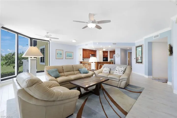 Living room featuring ceiling fan, ornamental molding, and light wood-type flooring
