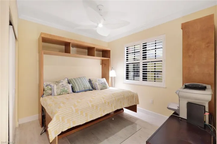 Bedroom featuring ceiling fan, hardwood / wood-style flooring, and crown molding