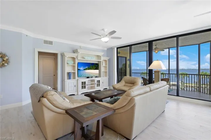 Living room featuring a wealth of natural light, ornamental molding, ceiling fan, and a water view