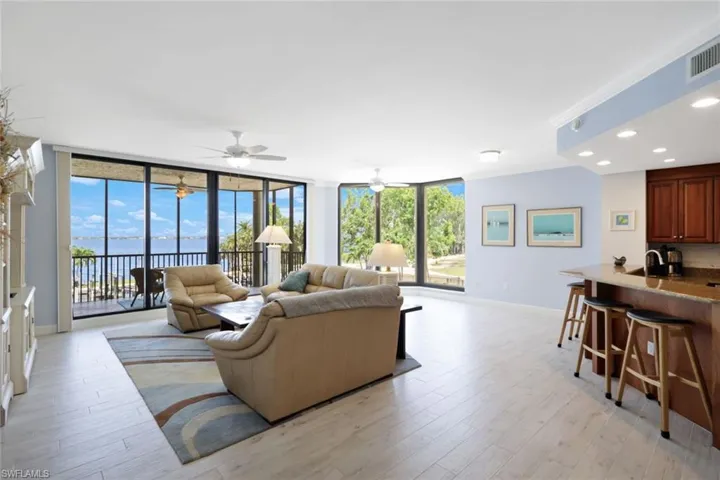 Living room featuring floor to ceiling windows, plenty of natural light, ceiling fan, and light wood-type flooring