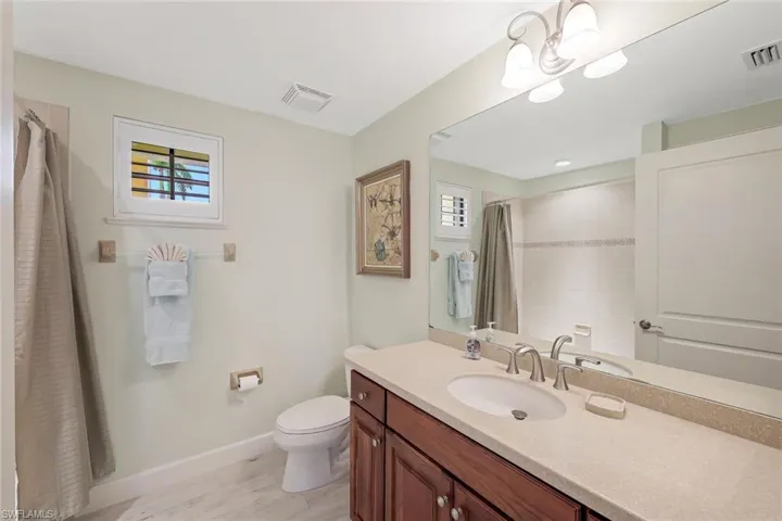 Bathroom featuring plenty of natural light, vanity, toilet, and a chandelier