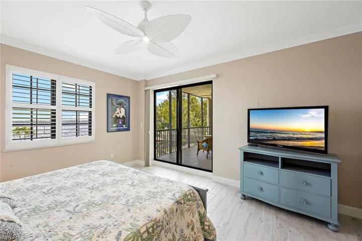 Bedroom with light wood-type flooring, ornamental molding, ceiling fan, and access to exterior