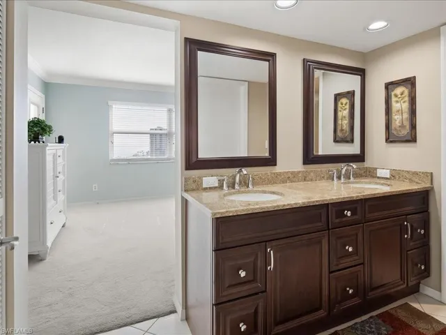 Bathroom featuring double vanity, light carpet, and light tile patterned flooring