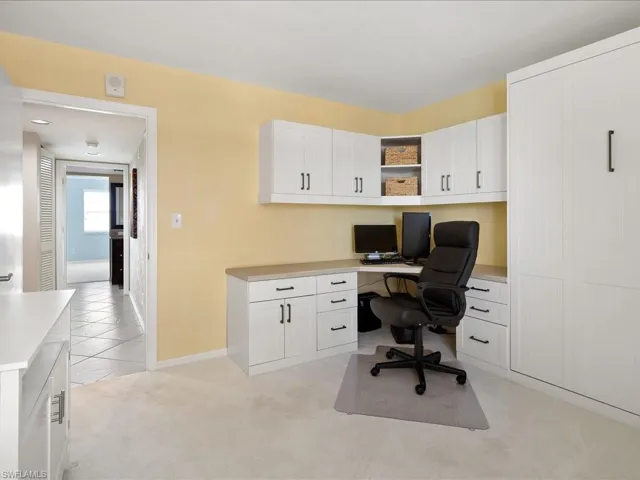 Office area featuring light carpet, built in desk, and light tile patterned floors