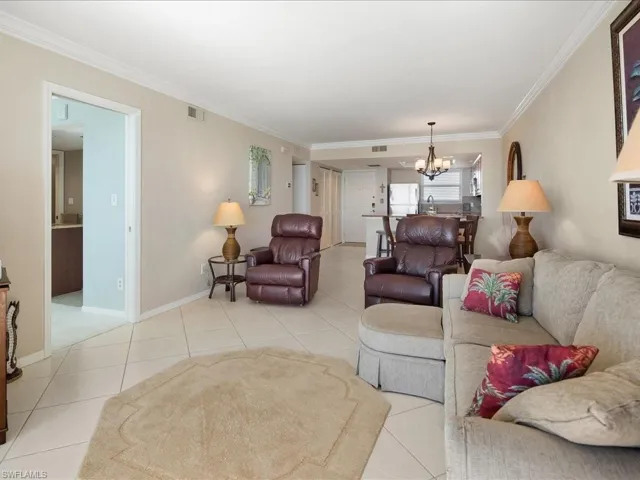 Living area with ornamental molding, a chandelier, and light tile patterned floors