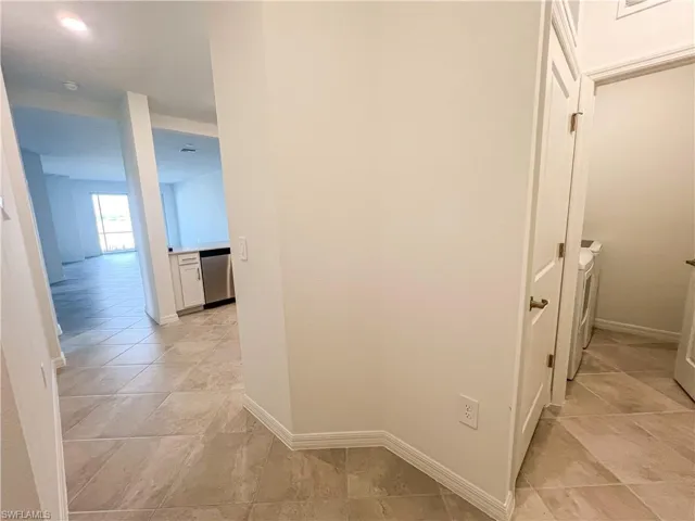Corridor featuring washer and dryer and light tile patterned floors