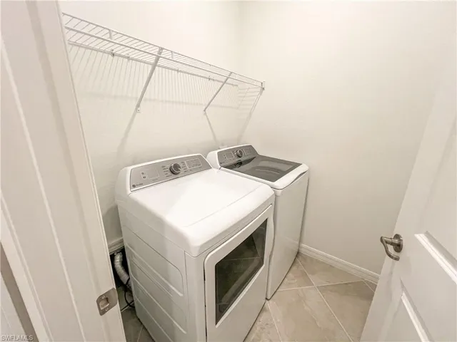 Laundry room featuring washing machine and dryer and baseboards