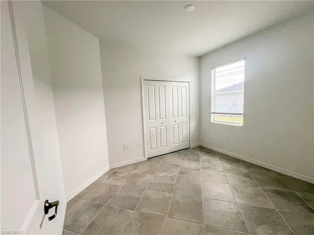 Unfurnished bedroom featuring a closet and light tile patterned flooring