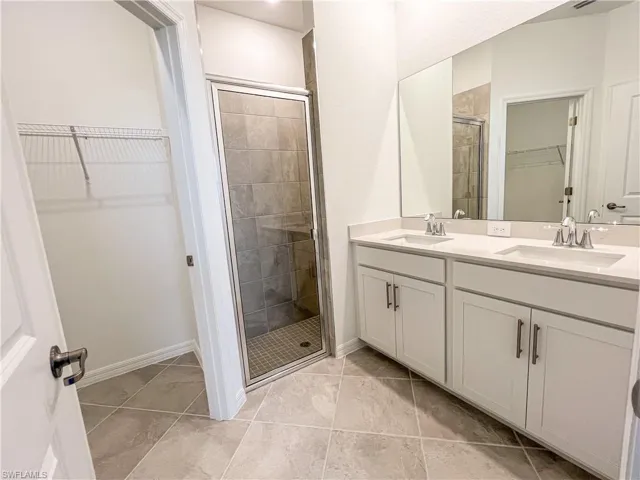 Full bath with a walk in closet, double vanity, and a stall shower