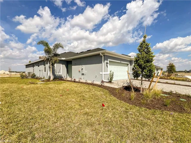 View of property exterior featuring stucco siding, an attached garage, concrete driveway, and a lawn