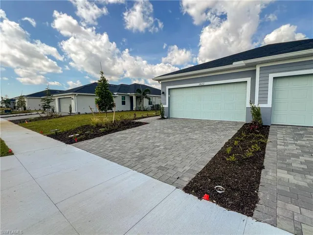 View of front of home featuring decorative driveway, a front yard, a garage, and stucco siding